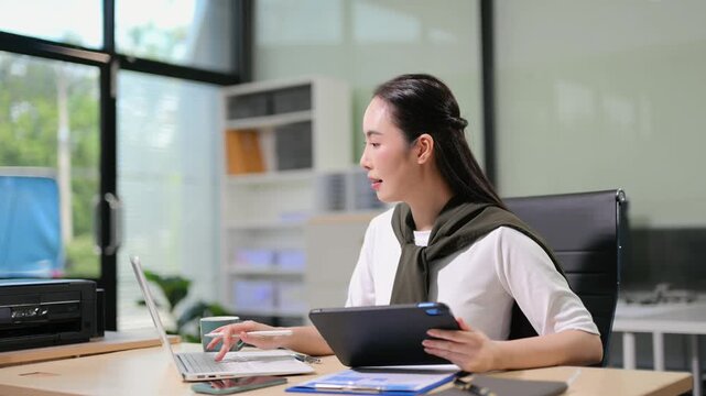 Business woman using tablet and laptop for doing math finance on an office desk, tax, report