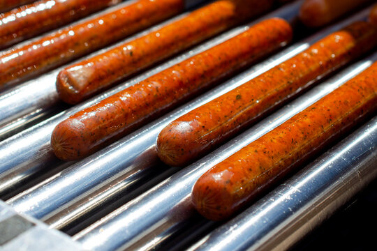 Hot dogs cooking on roller grill, fast food and concession stand concept, quick meal preparation, american cuisine.