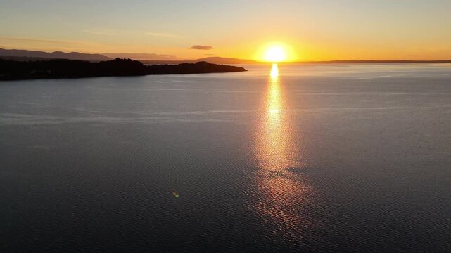 Aerial view of golden sunset reflecting on calm lake, Pucon, Chile.