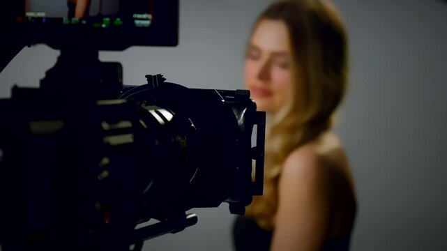 Filming in a professional film studio. Model posing as the camera operator records the video