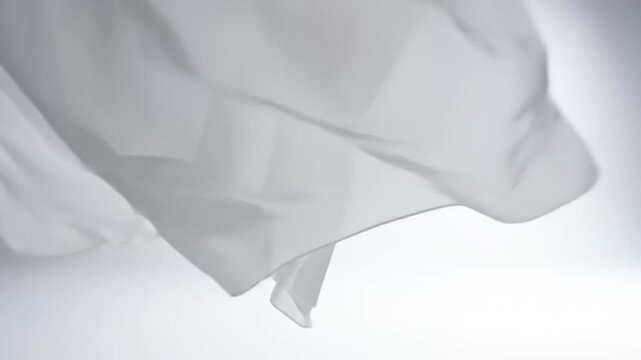 A white cloth waves gently in the air against a plain background.
