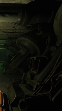 A collection of large machines sits in a dimly lit area with cables hanging from the ceiling. The ground shows signs of wear and the space is tight with various equipment.
