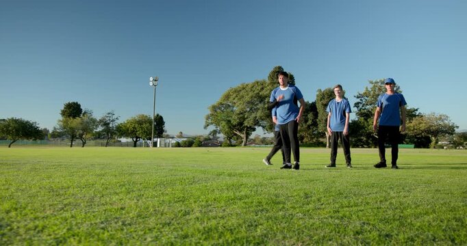 Triggered by rolling red ball, diverse male teammates chasing it in fielding drill