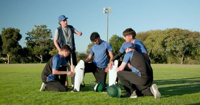Diverse cricket team clapping as coach directing, players fastening pads on field for drill