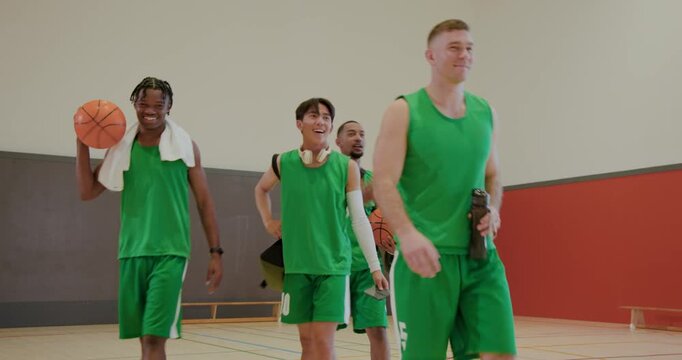 Scrambling for loose ball on court, diverse male team in green jerseys, sharing water bottle