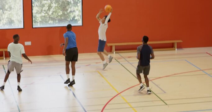 Diverse male athletes sprinting dribbling shooting layup and rebounding on court under mounted hoop