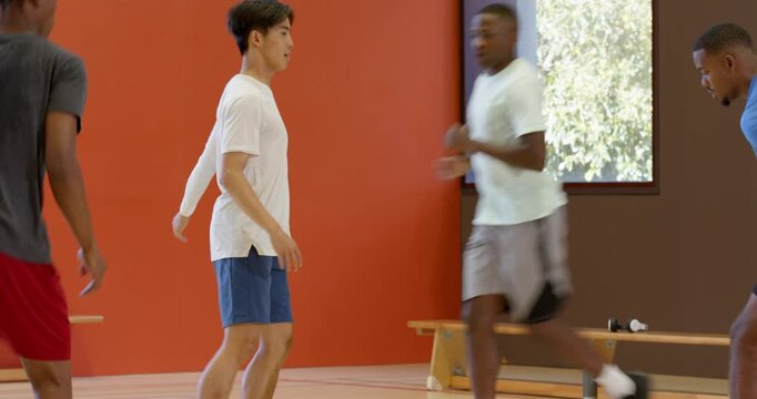 Reacting to attacker dribbling basketball, diverse men defending aiding teammate on court