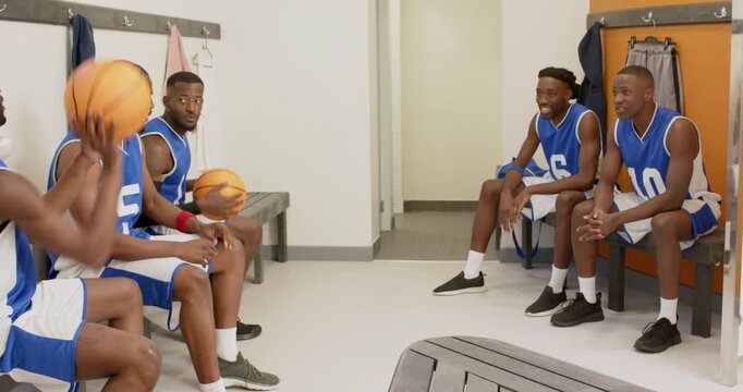 Warming up by bouncing ball african american basketball teammates passing high fives