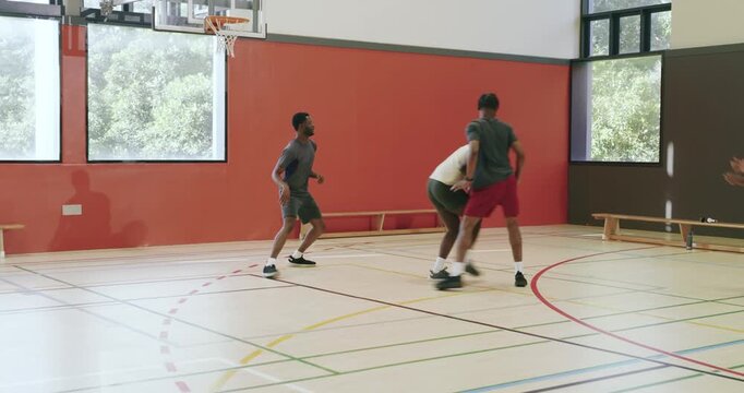 Bounce pass sparking diverse male friends shooting, rebounding and securing ball in the gym