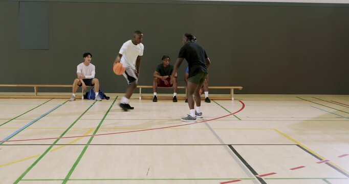 Men receiving inbound pass dribbling to basket at gym as rival defending forcing turnover