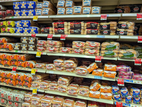 Quebec, Canada, 13 June 2026 : Grocery store shelves display various packaged bread products, including sliced bread, hamburger buns, and hot dog buns.