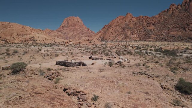 Aerial view of a traditional himba village with huts at the spitzkoppe mountains in the namibian desert during a sunny day