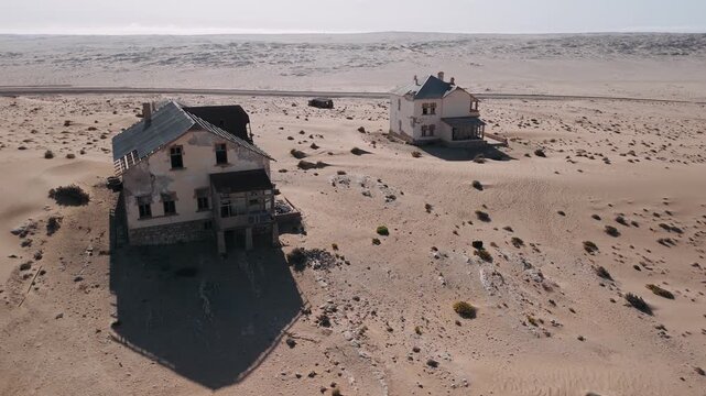 Aerial view of abandoned kolmanskop ghost town houses being swallowed by sand dunes in the namib desert of namibia