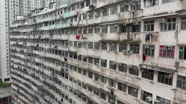 Drone flight past windows, laundry, and air conditioning systems of small apartment buildings in old residential neighborhood of Hong Kong island