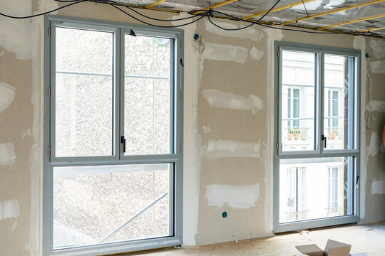 Espace en r&eacute;novation montrant des travaux sur les fen&ecirc;tres, les murs et la toiture, illustrant un chantier de transformation et de restauration d&rsquo;un b&acirc;timent.