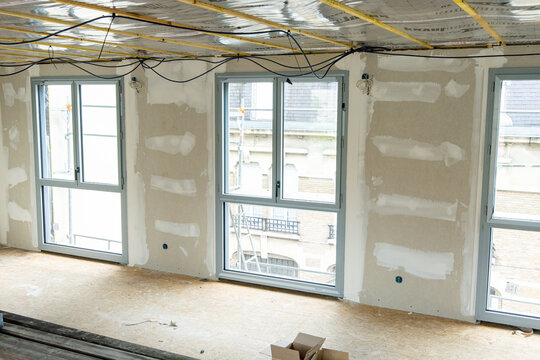 Espace en r&eacute;novation montrant des travaux sur les fen&ecirc;tres, les murs et la toiture, illustrant un chantier de transformation et de restauration d&rsquo;un b&acirc;timent.