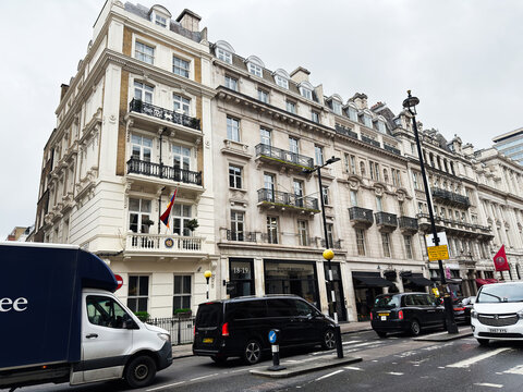 City street with historic white stone buildings, balconies and traffic in London, UK