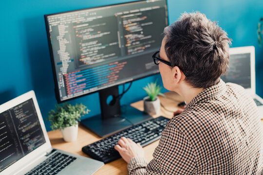Focused developer coding at a desktop with multiple monitors in a bright home office environment