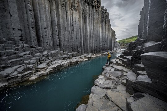 Tourist standing by the river in Stu&eth;lagil Canyon, turquoise blue river between basalt columns, Egilsstadir, Iceland