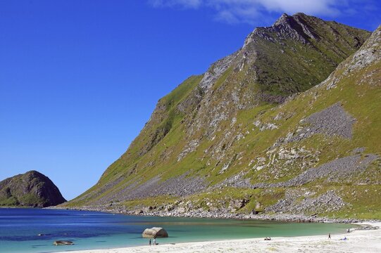 A long beach in front of towering mountains under clear skies, Haukland, Leknes, Vestv&aring;g&oslash;ya, Lofoten, Nordland, Norway