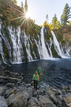 Young woman standing at a waterfall, McArthur-Burney Falls Memorial State Park, California, USA