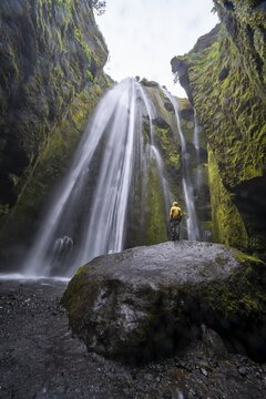 Hiker on a rock, Glj&uacute;frab&uacute;i waterfall, South Iceland, Iceland
