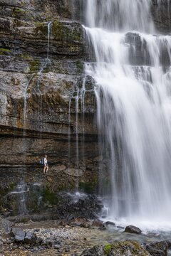 Little hiker in front of large Cascata di Mezzo waterfall, long exposure, Vallesinella, Brenta, Trentino, Italy