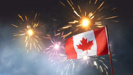 Obraz premium The national flag of Canada waving on a flagpole against a backdrop of bright, colorful fireworks exploding in the night sky during a celebration
