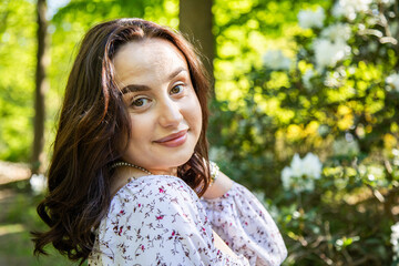 Fototapeta premium Beautiful young woman with pearl necklace posing by white azalea flowers