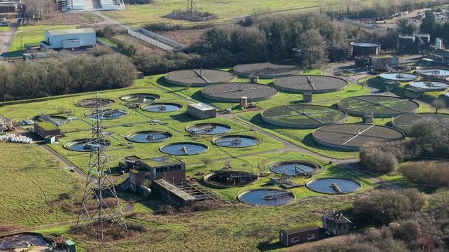 Aerial view of a large wastewater sewage treatment plant with circular clarifiers and sedimentation tanks in England