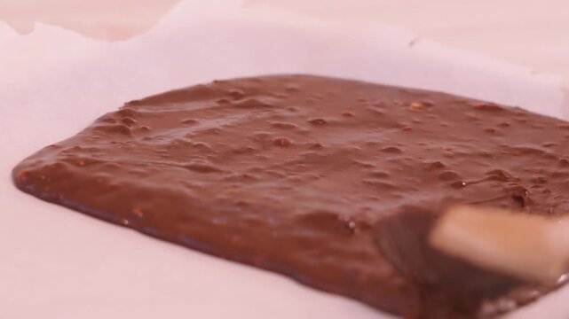 Timelapse of Spreading Rich, Glossy Dark Chocolate Brownie mix onto a tray lined with white greaseproof paper. Perfect for Home Baking Cooking Tutorials and Recipe Video Concepts. 4K.
