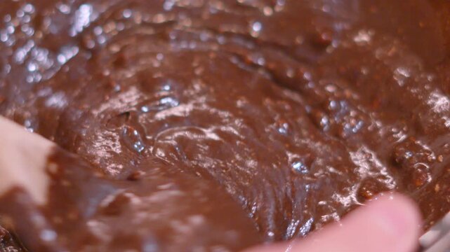 Stirring Homemade Chocolate Brownie Mix in Glass Bowl with Wooden Spoon in Slow Motion &ndash; Close Up. Glossy fudge batter, perfect for cooking tutorials and recipe video concepts. Satisfying Textures.