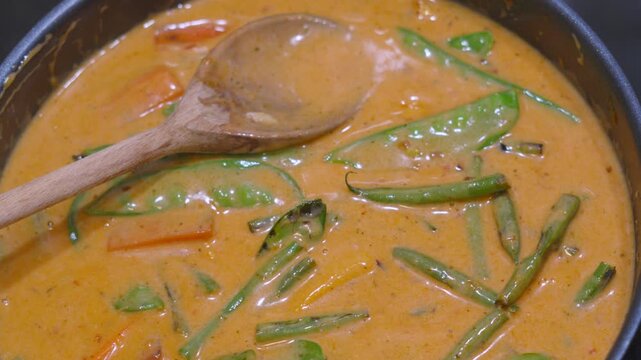 Vegetable Thai Red Curry Simmering in Hot Pan with Green Beans, Mangetout, Carrots, Baby Sweetcorn. Classic Asian Food.