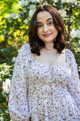 Fototapeta premium Beautiful young woman with pearl necklace posing by white azalea flowers