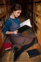 Student girl with open book in university library. © Nomad_Soul