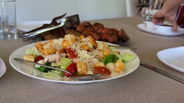 Plate of Caesar salad featuring crisp romaine lettuce, juicy grilled chicken pieces, cherry tomatoes, crunchy croutons, and a generous sprinkle of grated cheese.