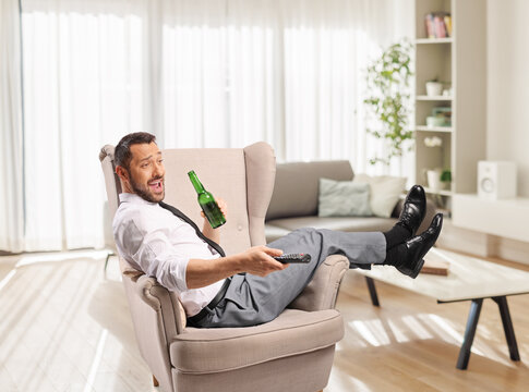 Man relaxing in an armchair after a ling day at work with a beer