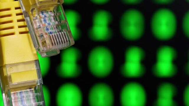 Close-up view of a yellow Ethernet cable connector against a backdrop of green digital symbols, illustrating the concept of network connectivity, data transmission, and modern communication.