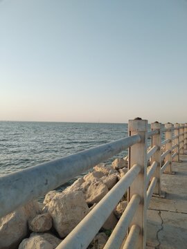 Ocean view from a seaside railing with clear blue water and bright daylight