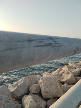 Close-up perspective of a seaside barrier with ocean and horizon in the background.