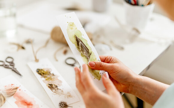 Woman Looking At A Bookmark She Made By Hand