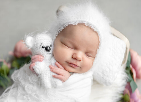 Newborn Baby Girl Smiling And Sleeping In A Crib With Flowers During A Photoshoot