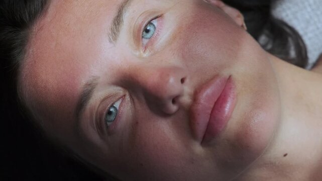 Young woman lying on sofa in soft sunlight experiencing quiet emotional shift, introspection, calm awareness and mental reset concept