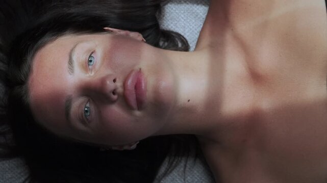 Young woman lying on sofa in soft sunlight experiencing quiet emotional shift, introspection, calm awareness and mental reset concept