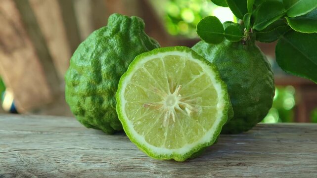Fresh kaffir lime fruits with leaves on wooden table background.