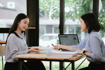 Obraz premium HR manager interviewing a job candidate across a desk, discussing qualifications and experience during a recruitment meeting in a modern office environment.
