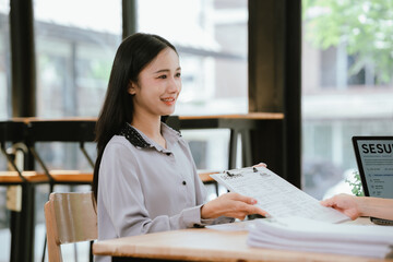 Obraz premium Smiling young job candidate holding a resume during an interview, expressing confidence, professionalism, and career opportunity in a modern office environment.