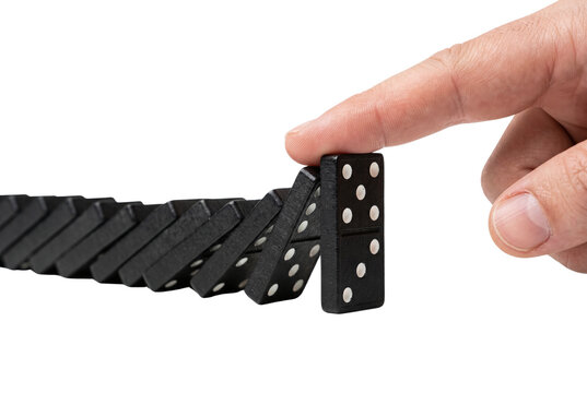 Finger pushing black domino to start a chain reaction