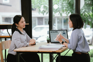 Obraz premium HR manager interviewing a job candidate across a desk, discussing qualifications and experience during a recruitment meeting in a modern office environment.
