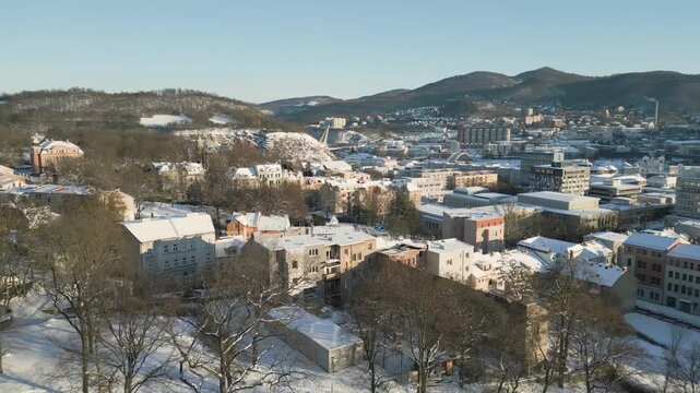An elevated drone winter view of the open-air summer cinema in &Uacute;st&iacute; nad Labem shows rows of empty, snow-covered amphitheater seating and a large projection screen under a massive metal roof structure 